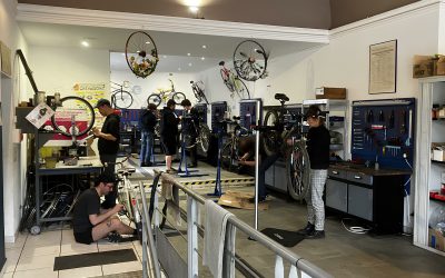 Photo de l'atelier de la Maison du vélo, où on peut voir plusieurs personnes en train de réparer des vélos.
